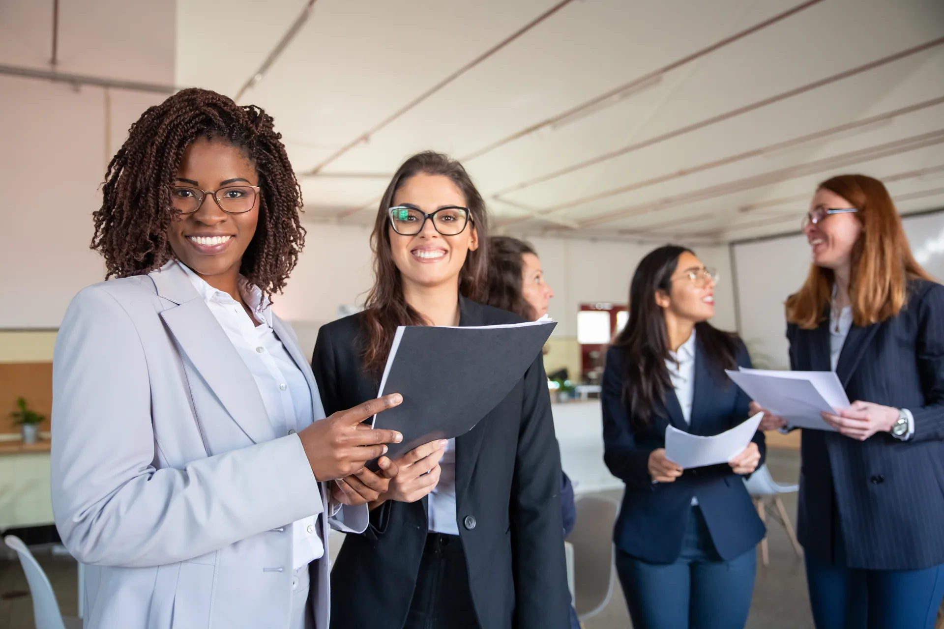 Professional women from different backgrounds collaborating with documents in a modern office